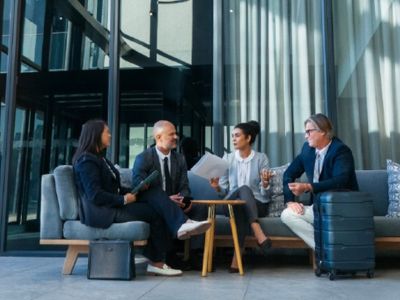 Quattro persone con abiti da lavoro conversano su un divano
