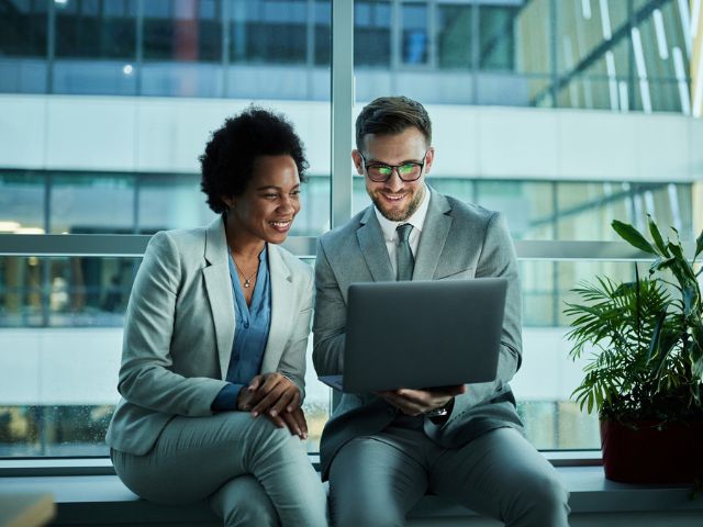 Due persone che guardano lo schemo del computer e sorridono