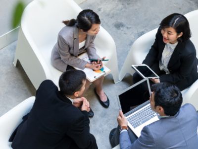 Pessoas de negócios sentadas com portatil a falar sobre o Seguro de Crédito