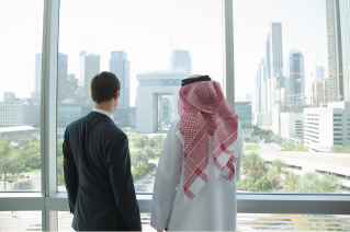 2 people in an office, looking towards the view from outside to Dubai International Financial Center 