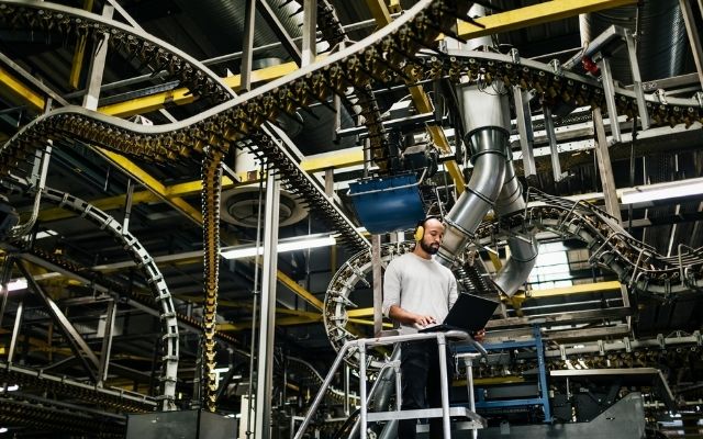 Man in factory production line. He is working on computer system
