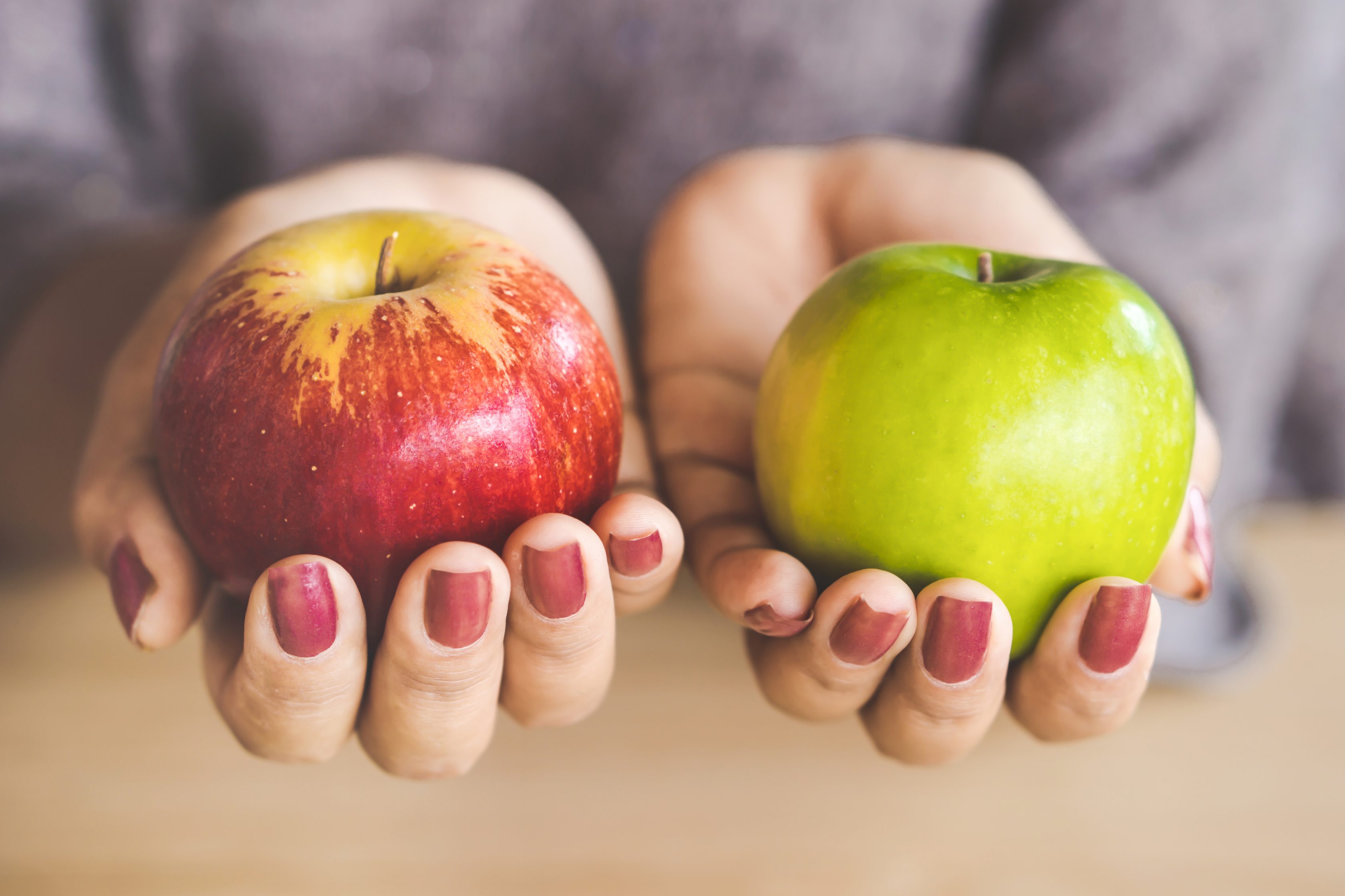 two hands holding two apples 