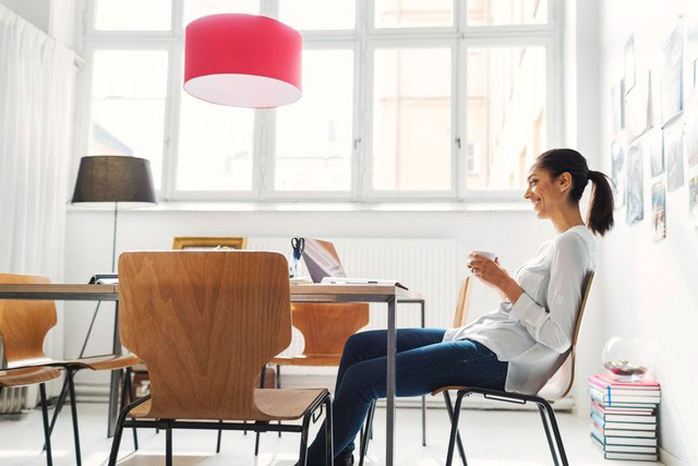 white female with coffee cup in hand looking at computer