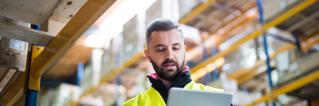 man in high-vis vest looking down at tablet