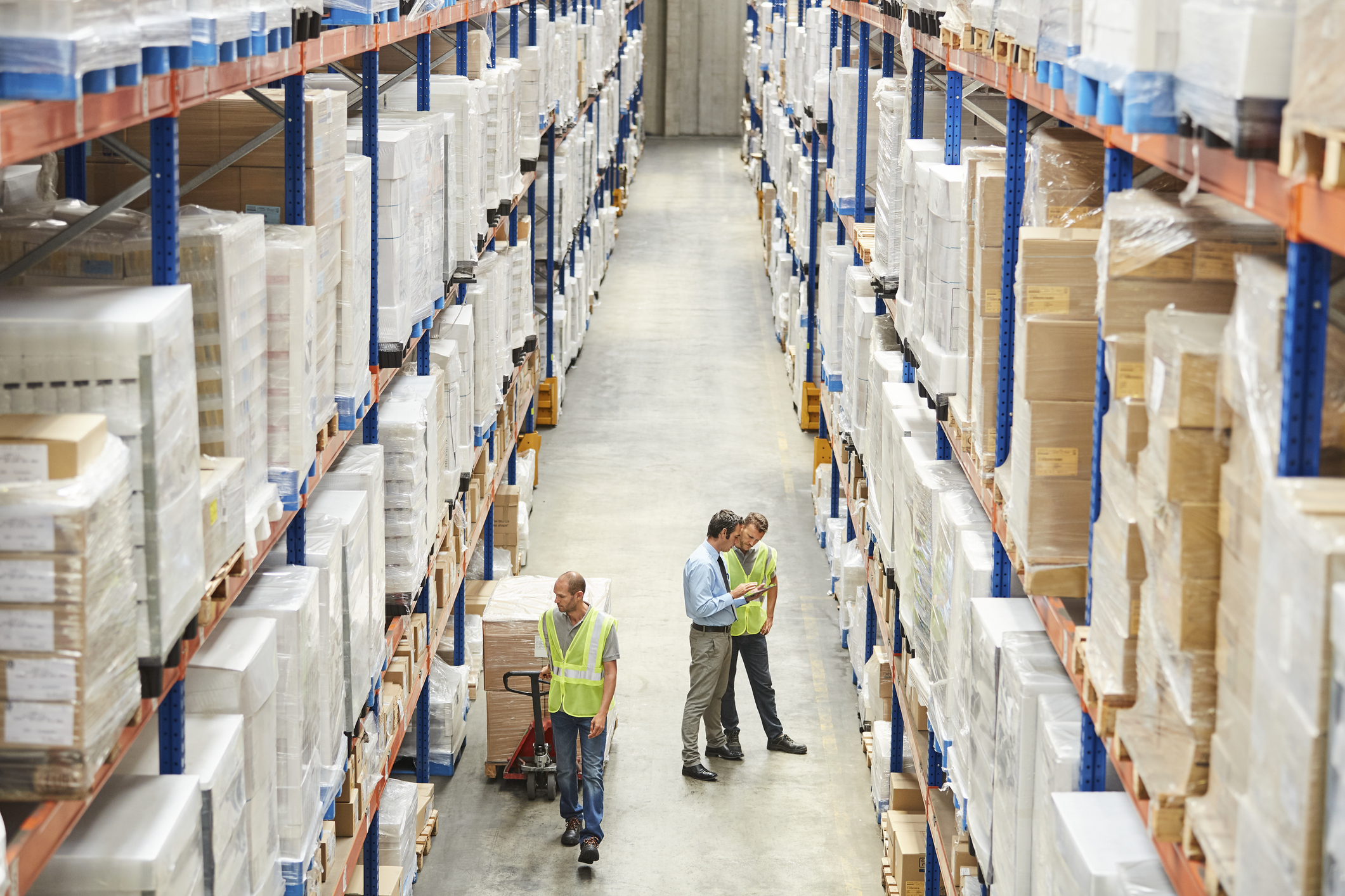warehouse workers looking at inventory in middle of row inside of warehouse