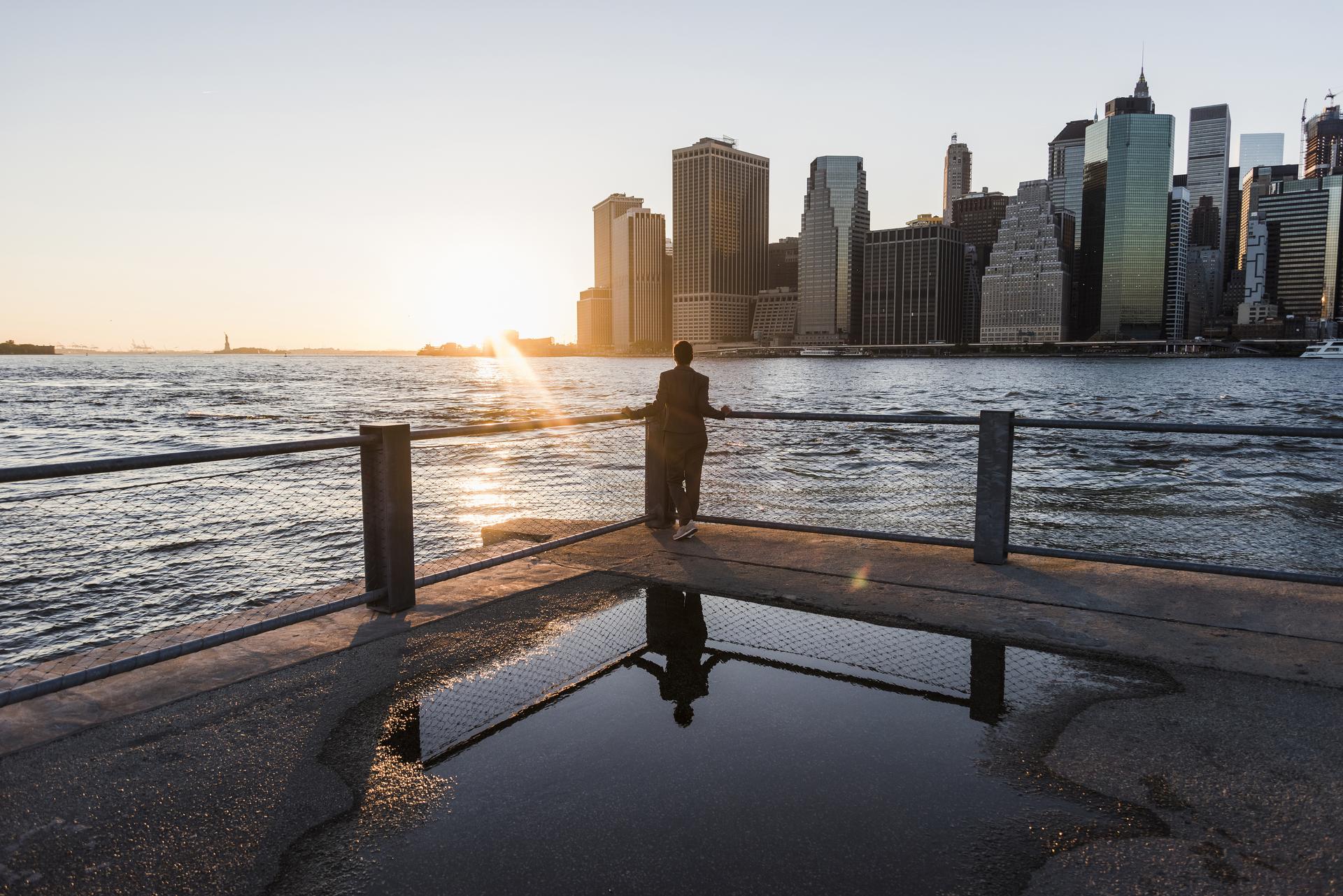 sun setting with city and body of water