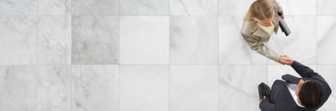 Top view of a businessman and woman shaking hands in office lobby