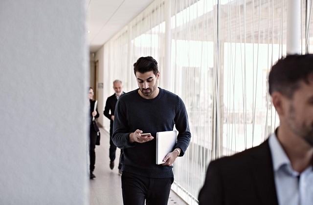  Um gestor verifica os seus e-mails no seu smartphone antes de entrar na reunião