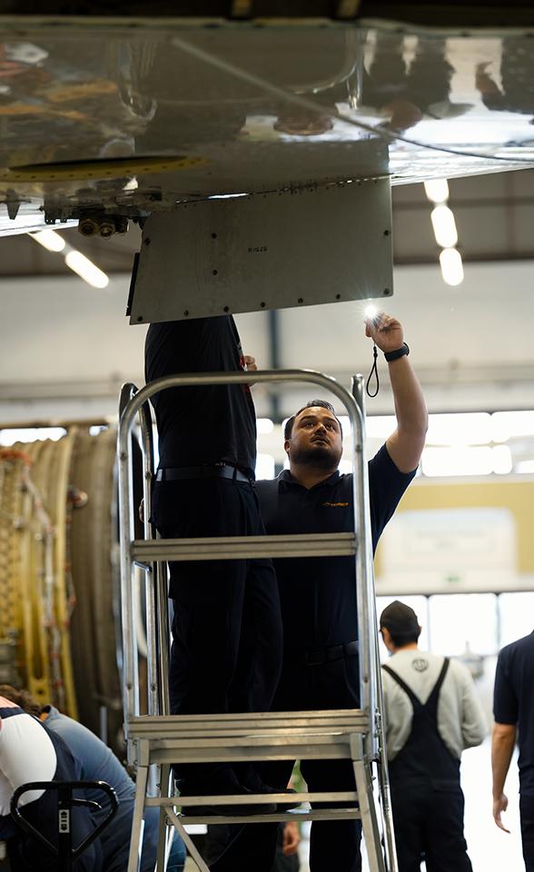 Flugzeugarbeiter am Flügel eines Flugzeugs