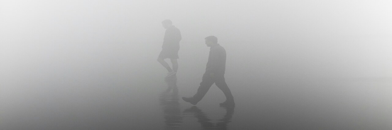 Deux hommes marchent dans le brouillard