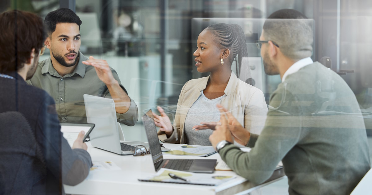 Des personnes qui discutent autour d'une table, face à des ordinateurs