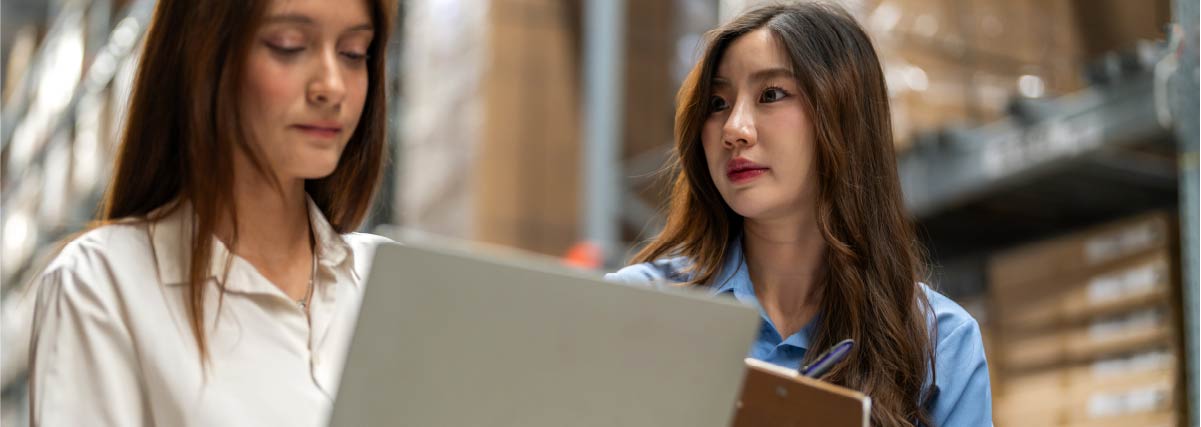 Deux personnes regardent un ordinateur dans un entrepôt