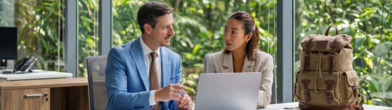 Deux personnes qui discutent autour d'une table, face à des ordinateurs