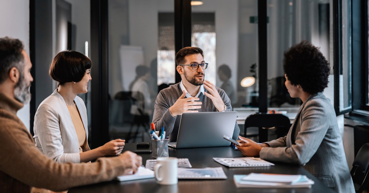 Des personnes qui discutent autour d'une table, face à des ordinateurs
